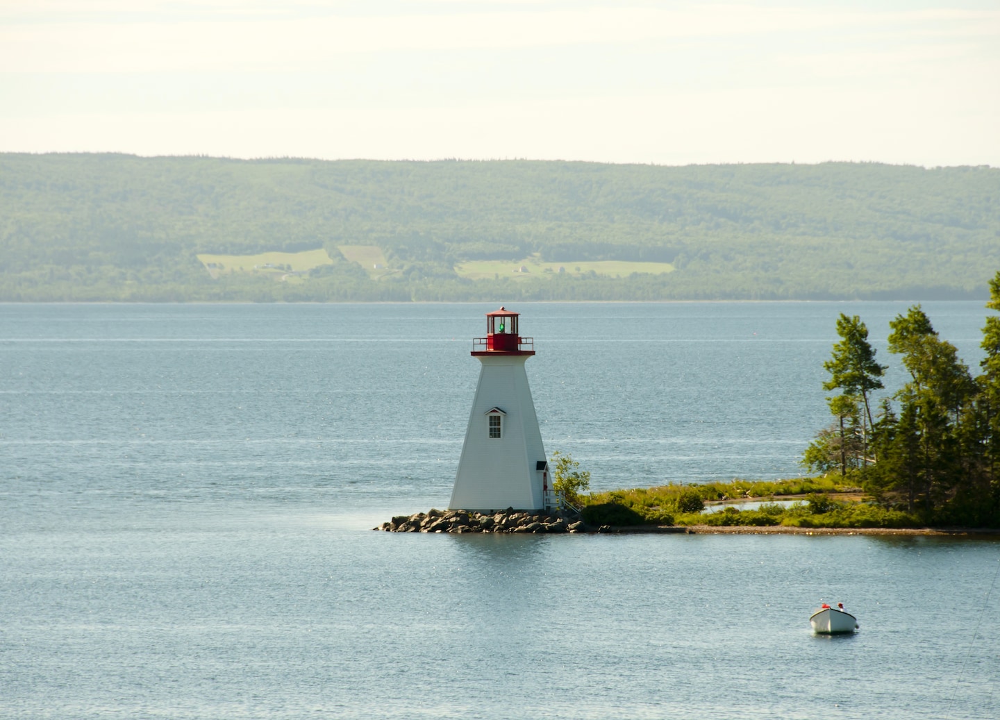 Baddeck Harbour shows calm blue water, anchored boats, and tree‑lined hills along the Nova Scotia shoreline. - Sydney, Nova Scotia