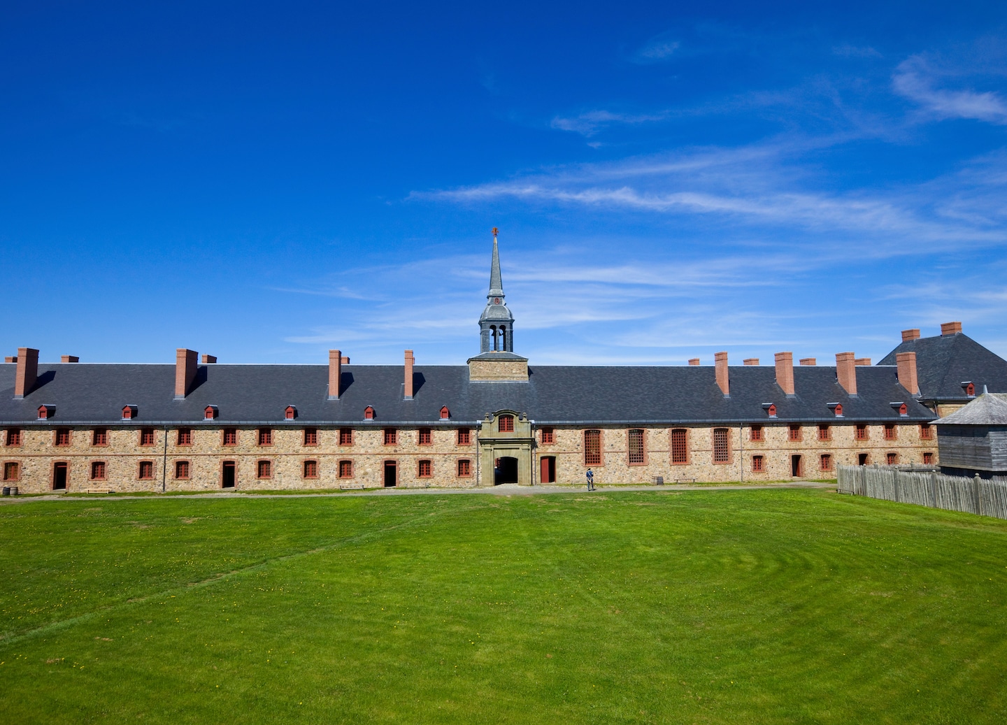 The Fortress of Louisbourg shows stone walls, wooden buildings, and grassy grounds from the 18th century. - Sydney, Nova Scotia