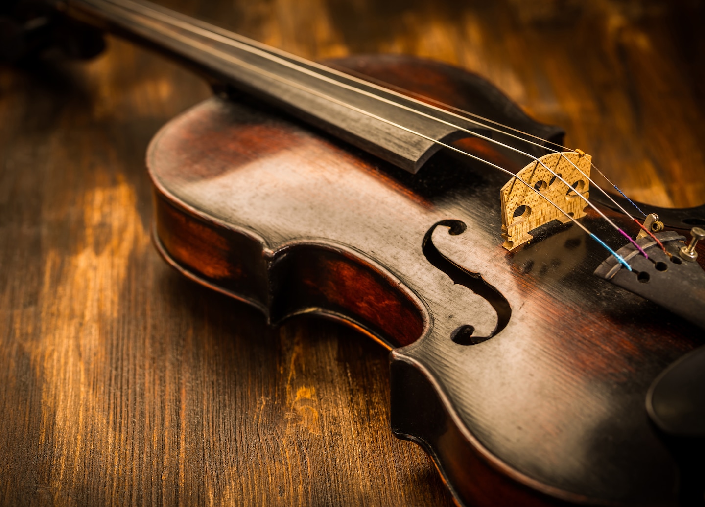 A vintage wooden violin rests on a textured wood surface, highlighting its warm, classic finish. - Sydney, Nova Scotia