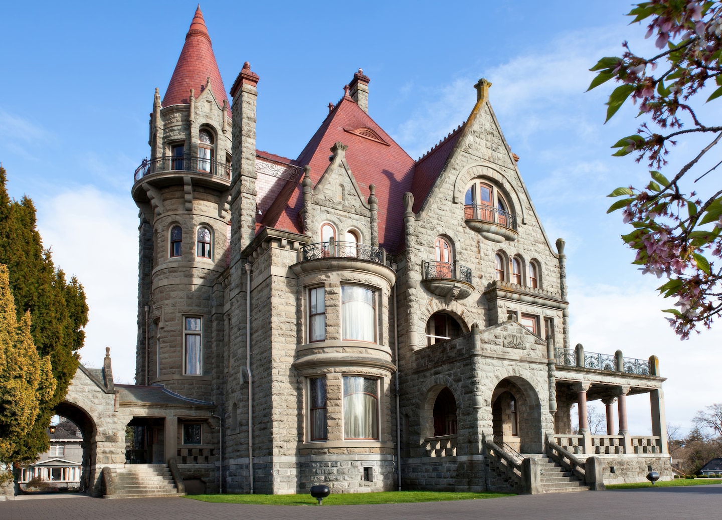 Craigdarroch Castle rising above trees with detailed stone architecture. - Victoria, British Columbia