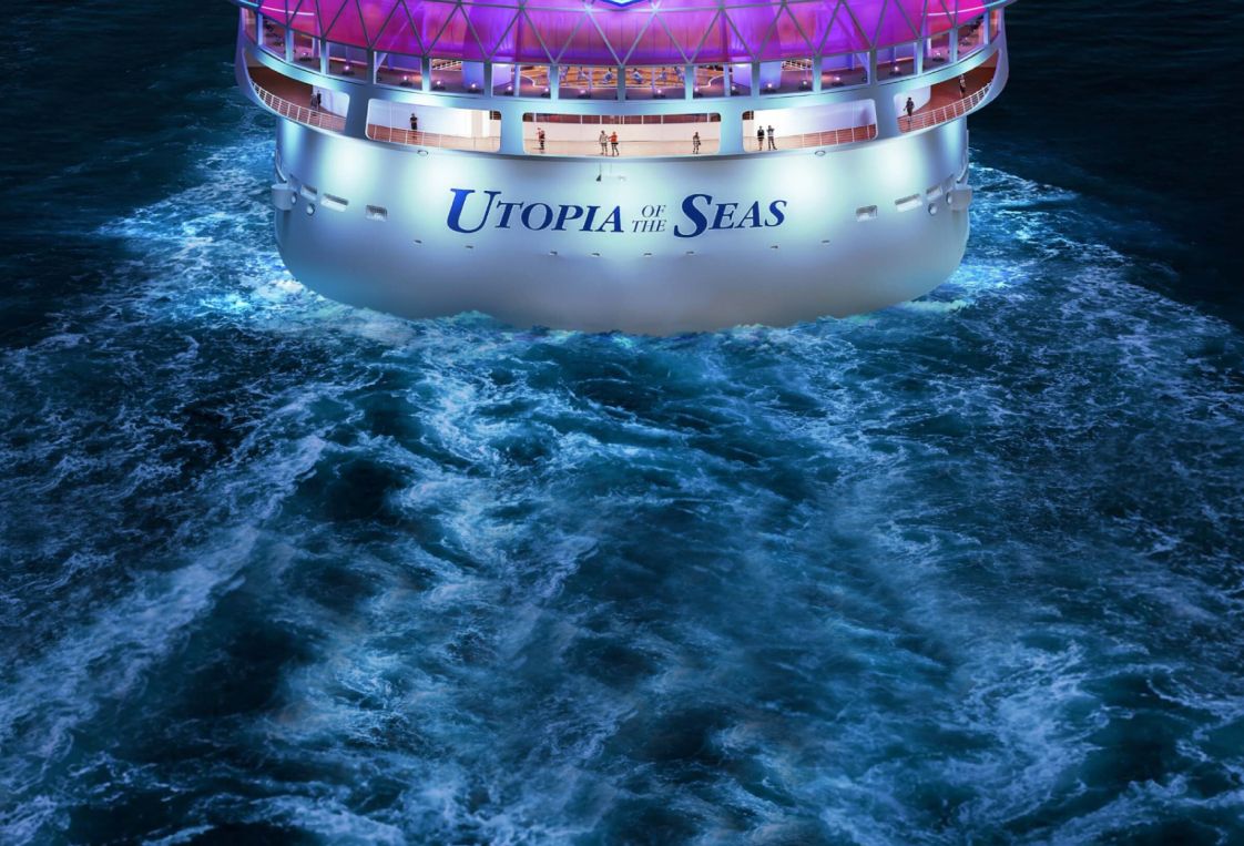 The back of a ship sailing through the water with the name Utopia of the Seas written across it. Utopia of the Seas.